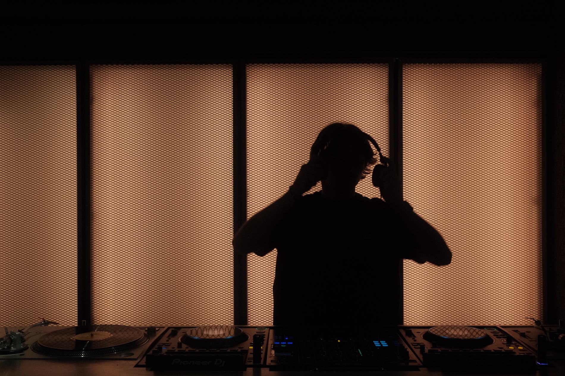 A DJ in silhouette against a glowing wall